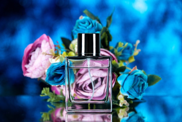 Vista frontal do frasco de perfume retangular com flores coloridas na foto azul