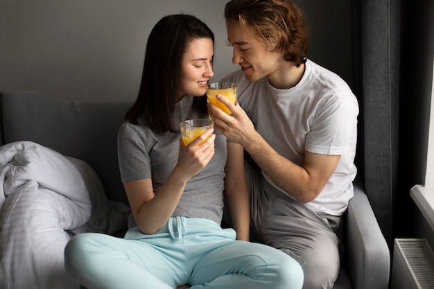 Vista frontal do homem dando suco de laranja para a namorada