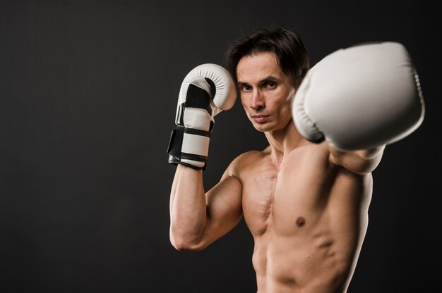 Vista frontal do homem musculoso sem camisa com luvas de boxe e espaço para texto