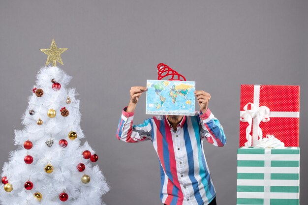 Vista frontal do homem natal com chapéu de Papai Noel em espiral cobrindo o rosto com o mapa