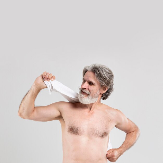 Vista frontal do homem sênior com toalha depois do banho