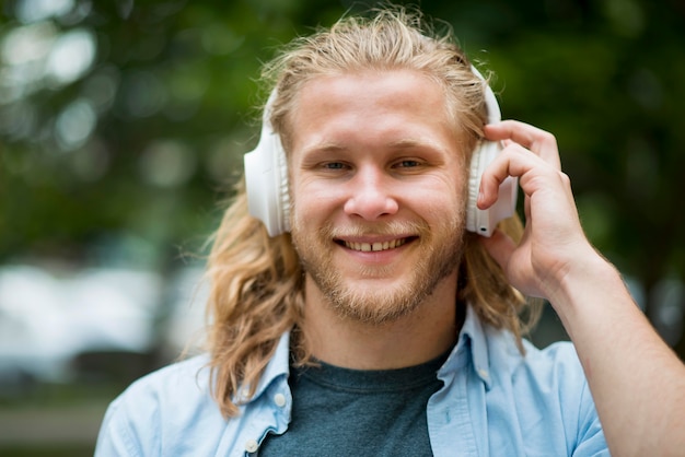 Vista frontal do homem sorridente com fones de ouvido ao ar livre