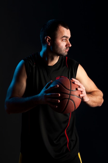 Vista frontal do jogador de basquete, posando com bola