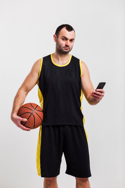Foto grátis vista frontal do jogador de basquete, posando com smartphone