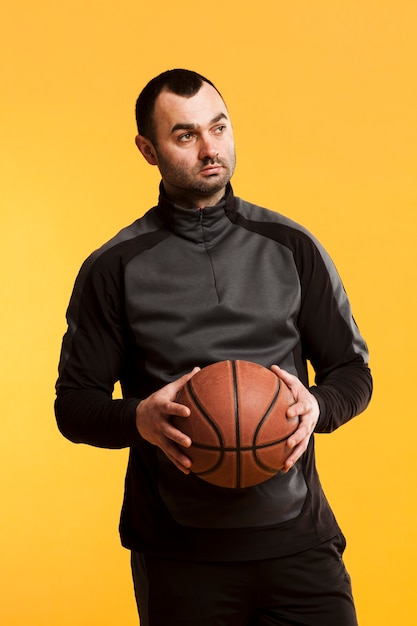 Vista frontal do jogador masculino posando com basquete