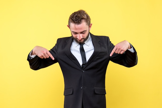 Foto grátis vista frontal do jovem empresário apontando os dedos para baixo em amarelo