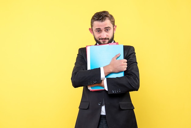 Vista frontal do jovem empresário olhando com confiança e segurando pastas em amarelo