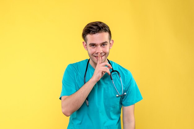 Vista frontal do jovem médico sorrindo na parede amarela