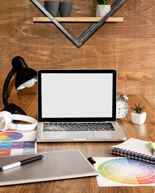 Vista frontal do laptop no espaço de trabalho do escritório com lâmpada e notebook