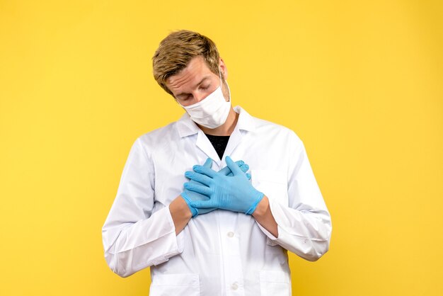 Vista frontal do médico cansado sobre fundo amarelo pandêmico médico saúde covid- vírus