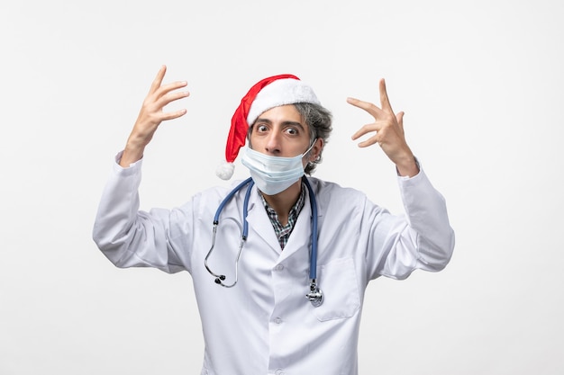 Vista frontal do médico com máscara na parede branca vírus do feriado de ano novo
