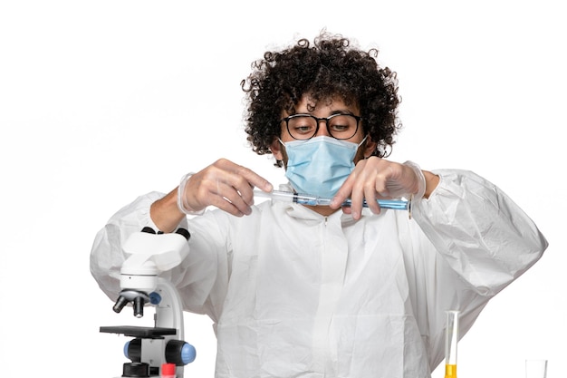 Vista frontal do médico do sexo masculino em traje de proteção e máscara de preenchimento de injeção com solução em fundo branco covid- vírus da pandemia epidêmica
