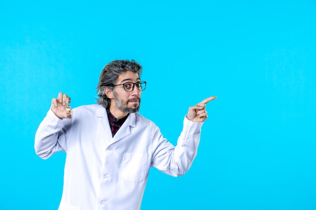 Foto grátis vista frontal do médico em uniforme médico segurando o pequeno frasco no azul