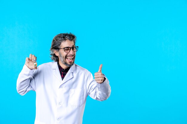 Vista frontal do médico em uniforme médico segurando o pequeno frasco no azul