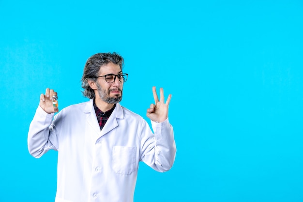 Vista frontal do médico em uniforme médico segurando o pequeno frasco no azul