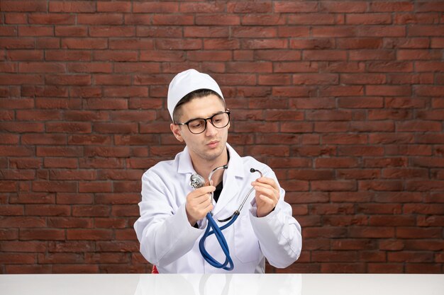 Vista frontal do médico masculino com terno branco e estetoscópio