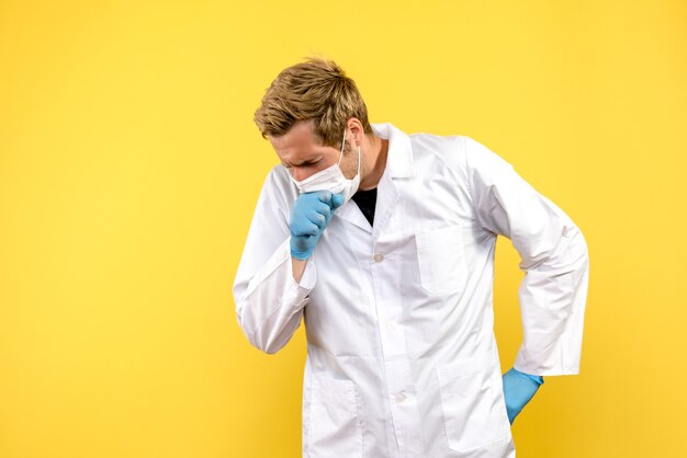 Vista frontal do médico tossindo em fundo amarelo pandemia de cobiçado médico de saúde