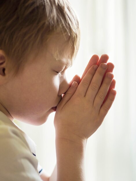 Vista frontal do menino rezando