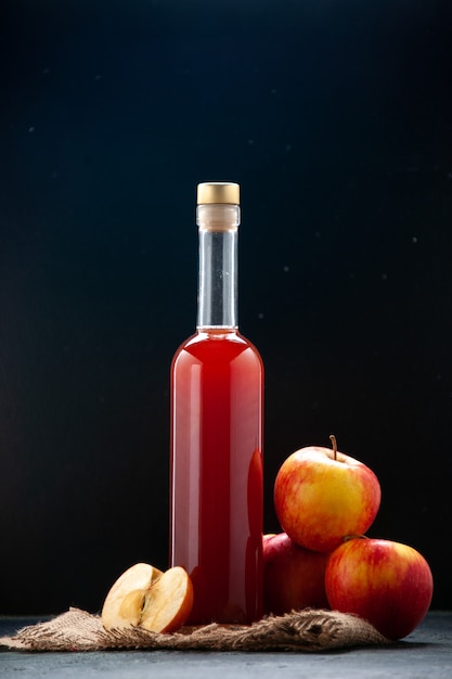 Vista frontal do molho de maçã vermelha em uma garrafa em uma superfície escura