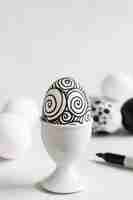 Foto grátis vista frontal do ovo monocromático para a páscoa em uma xícara de ovo com espaço de cópia