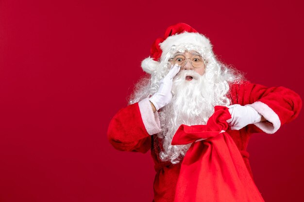 Vista frontal do papai noel abrindo uma sacola cheia de presentes para as crianças nas emoções do feriado vermelho de natal