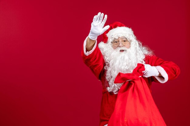 Vista frontal do papai noel abrindo uma sacola cheia de presentes para as crianças no feriado de emoção de natal vermelho