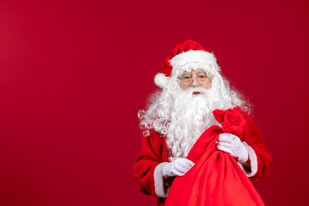 Vista frontal do papai noel carregando uma sacola vermelha cheia de presentes na emoção do feriado de ano novo de natal vermelho