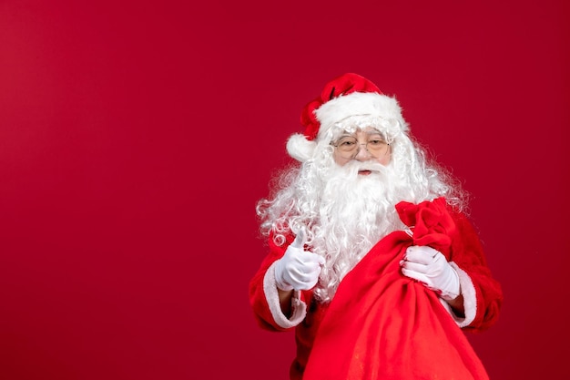 Vista frontal do papai noel carregando uma sacola vermelha cheia de presentes sobre as emoções do feriado de ano novo de natal vermelha