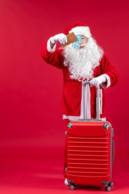 Vista frontal do Papai Noel com a bolsa segurando os ingressos e se preparando para a viagem na parede vermelha