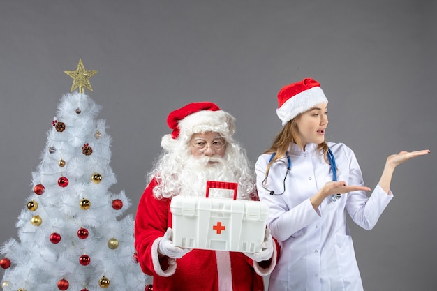 Vista frontal do Papai Noel com a médica que lhe deu o kit de primeiros socorros na parede cinza