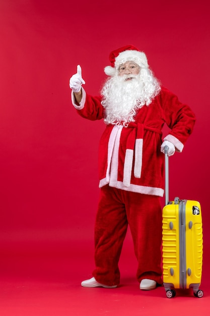 Foto grátis vista frontal do papai noel com bolsa amarela se preparando para a viagem na parede vermelha