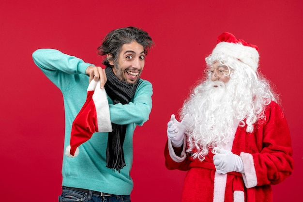 Vista frontal do Papai Noel com jovem em pé na parede vermelha