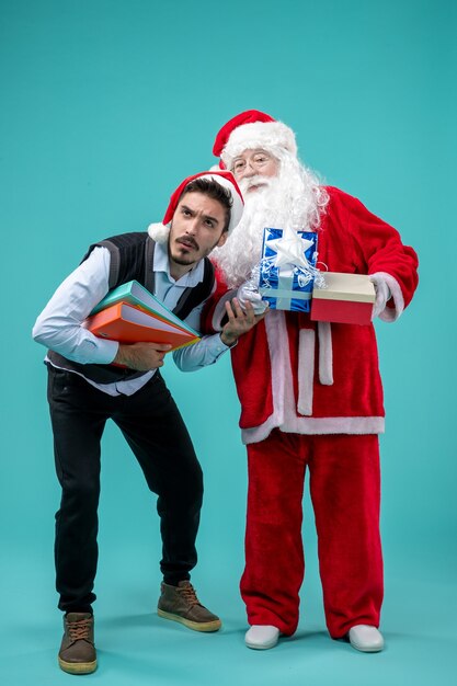 Vista frontal do papai noel com jovem macho e presentes no piso azul frio natal feriado férias neve ano novo