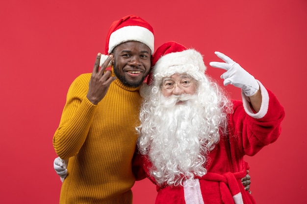 Vista frontal do papai noel com jovem na parede vermelha