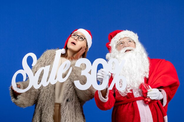 Vista frontal do papai noel com jovem segurando os escritos de venda na cor azul do feriado do Natal