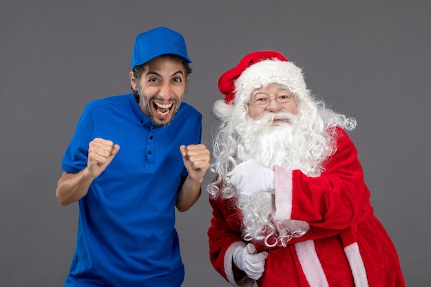 Vista frontal do papai noel com mensageiro masculino na parede cinza