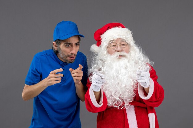 Vista frontal do Papai Noel com mensageiro masculino na parede cinza