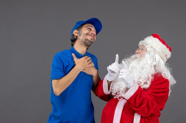 Vista frontal do Papai Noel com mensageiro masculino na parede cinza