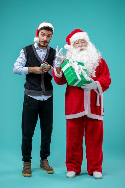 Foto grátis vista frontal do papai noel com o jovem e feriado presente na parede azul