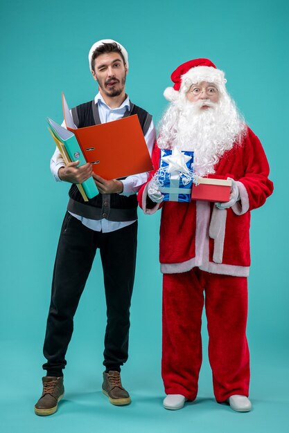 Vista frontal do Papai Noel com o jovem e presentes na parede azul