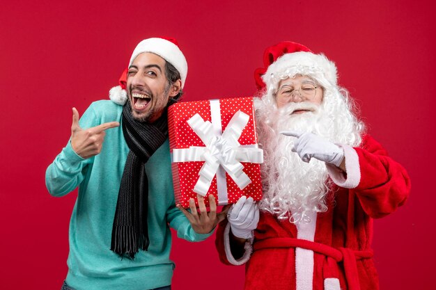 Vista frontal do papai noel com um homem segurando feriado presente na emoção vermelha presente vermelho Natal ano novo