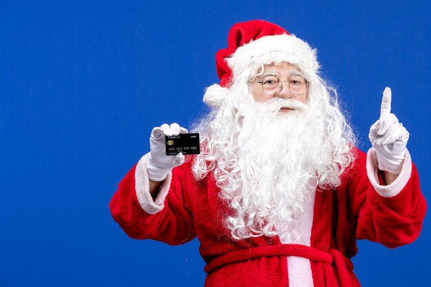 Vista frontal do papai noel em um terno vermelho segurando um cartão do banco na cor azul presente feriado de ano novo