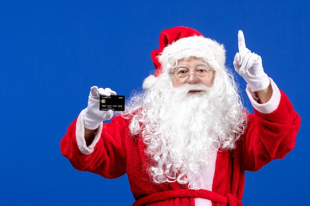 Vista frontal do papai noel em um terno vermelho segurando um cartão do banco no feriado azul presente na cor do Natal