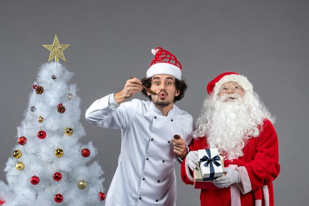 Vista frontal do papai noel em volta da árvore do feriado com cozinheiro