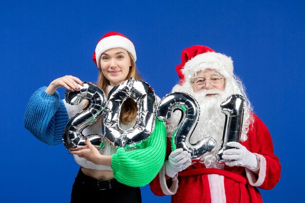 Vista frontal do Papai Noel junto com a jovem figura feminina segurando na parede azul