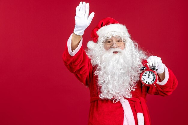 Vista frontal do papai noel segurando o relógio nas emoções do feriado de Natal vermelho