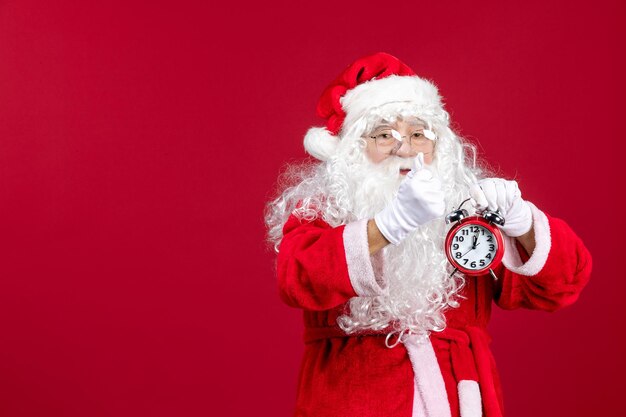 Vista frontal do papai noel segurando o relógio no feriado de natal vermelho