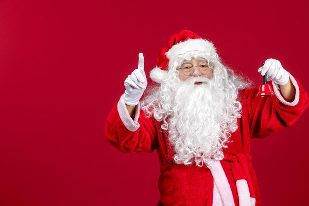 Vista frontal do papai noel segurando sininho no feriado de presente de ano novo de emoção vermelha