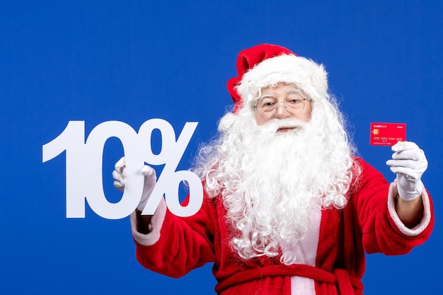 Vista frontal do papai noel segurando um cartão do banco e escrevendo sobre a cor azul no feriado presente no natal