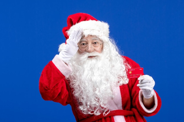 Vista frontal do papai noel segurando um cartão do banco vermelho na cor azul do ano novo, feriados de natal